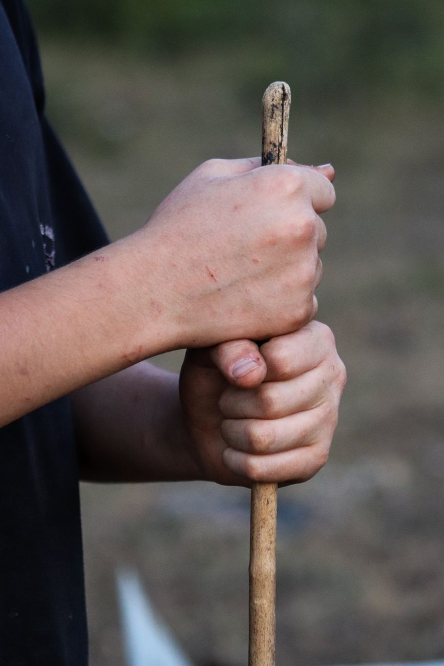 close up of hands holding rustic walking stick